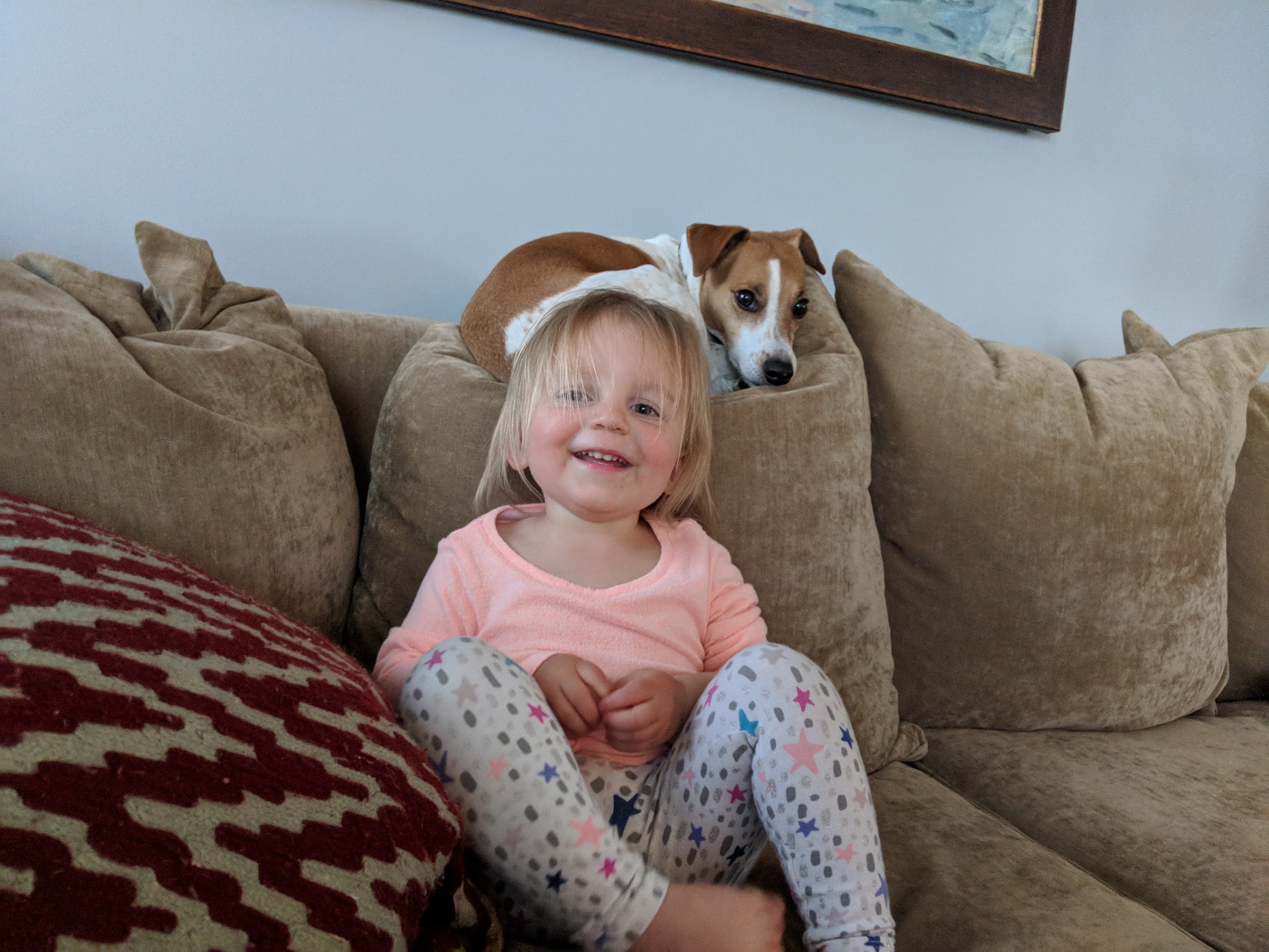 Seymour peeking over the couch cushions behind a smiling toddler